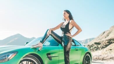 Tatyana Remley woman in black tank top and black pants sitting on green car hood during daytime