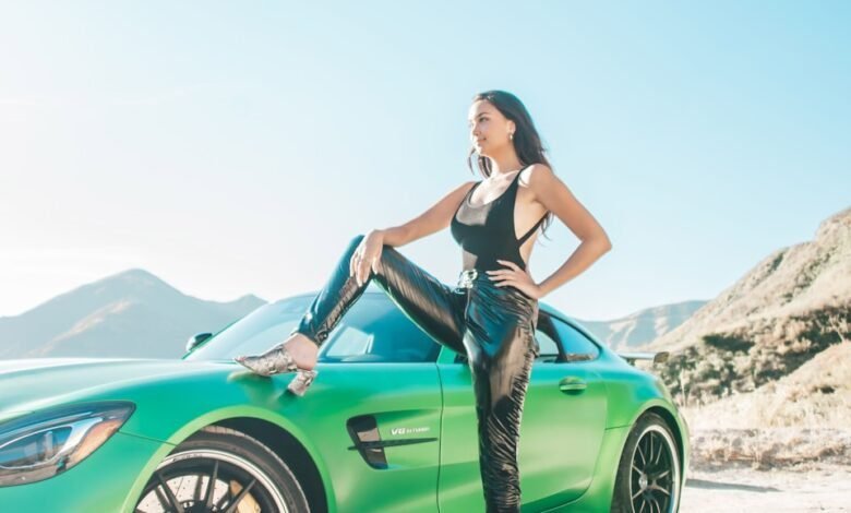 Tatyana Remley woman in black tank top and black pants sitting on green car hood during daytime