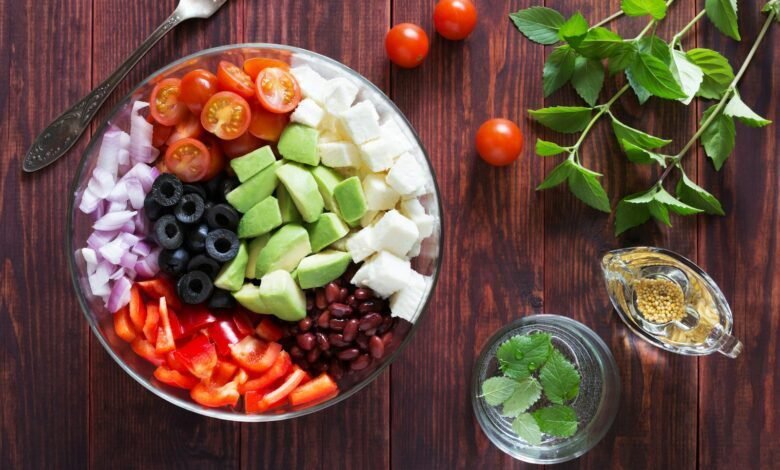 a bowl filled with vegetables and Salad Fork on top of a wooden table