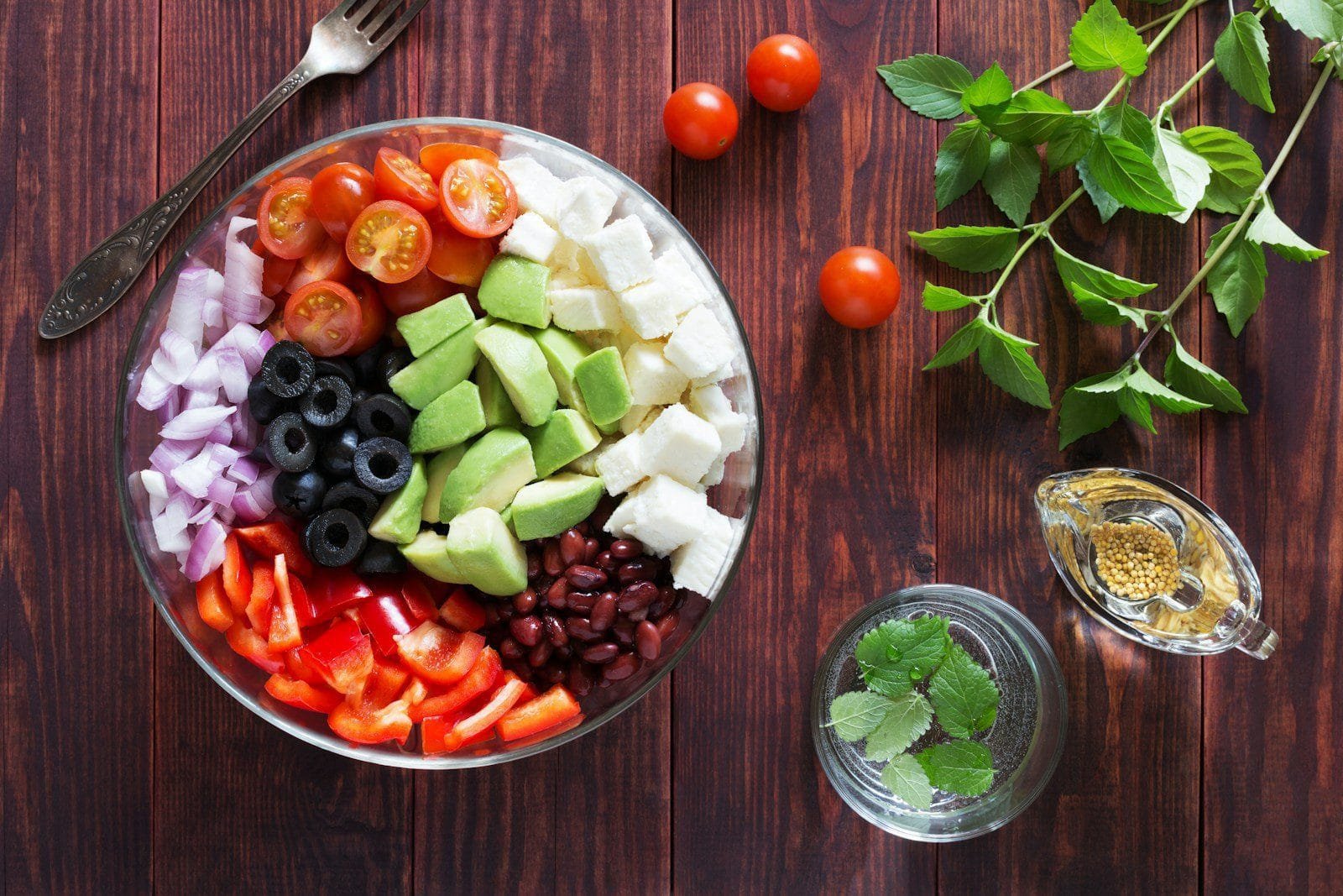 a bowl filled with vegetables and Salad Fork on top of a wooden table